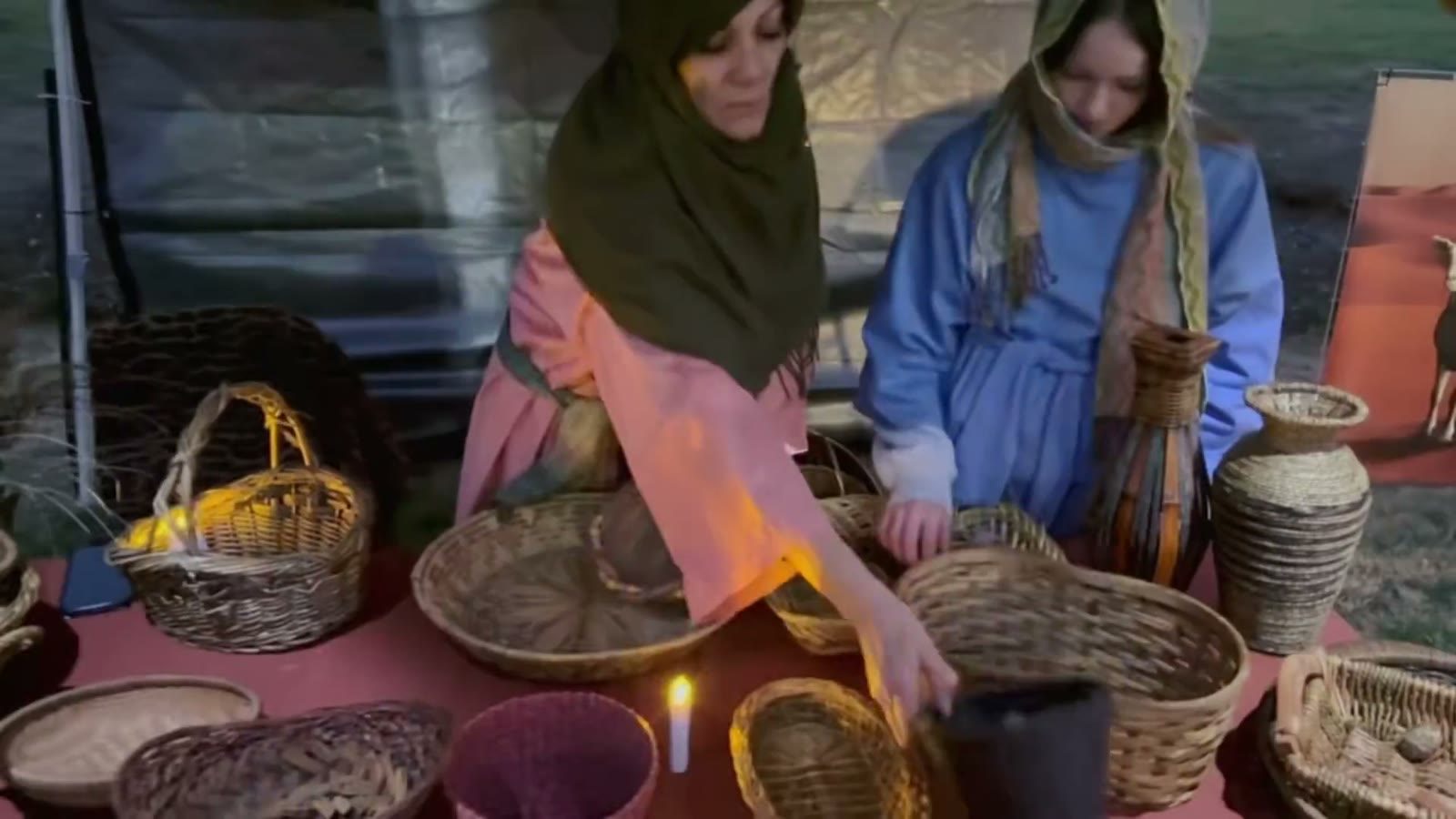 Two weavers sort baskets by candlelight